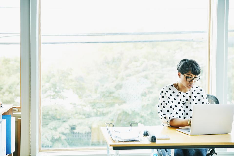 Mature businesswoman working on laptop at desk in creative studio