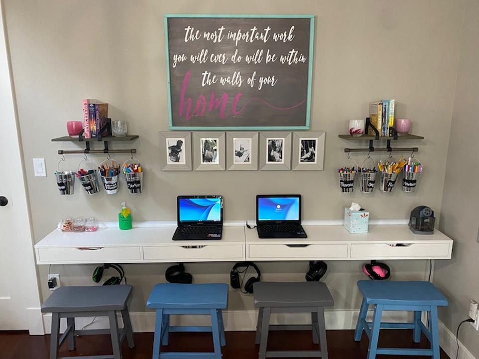 A homeschooling room with four stools, desks on the walls, phots, shelving, etc.