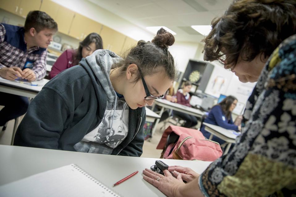 Teacher helping a student at her desk.