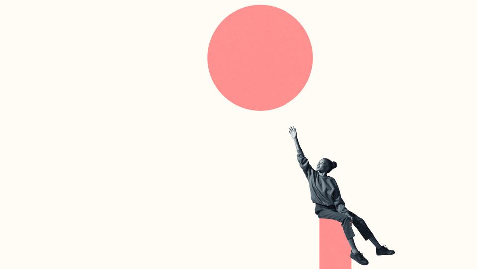 Woman sitting on column while reaching for circle