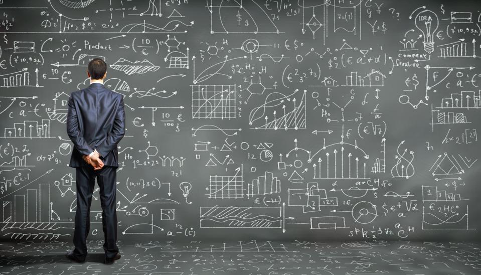 Man looking at a wall filled with mathematical information.