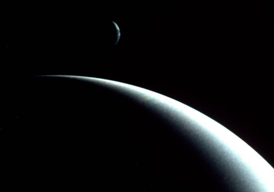 Las medias lunas iluminadas de Neptuno (primer plano) su mayor luna Tritón (fondo).