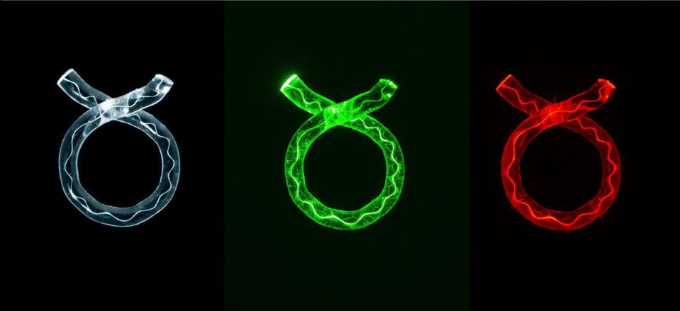 Three glass rings with a bright line inside each of them, in different coloured lights