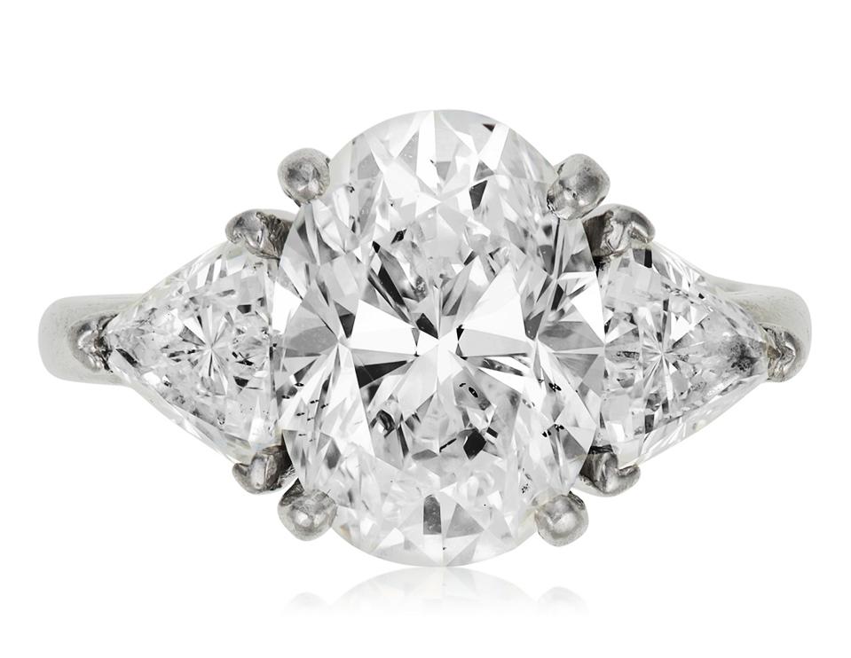 A 4.80-carat oval diamond mounted on a platinum ring and flanked by two diamonds
