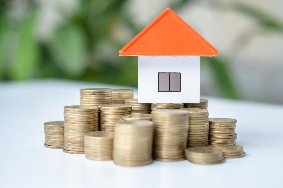 House and coins in the hands of investors.Orange roof house.Save money for buying a new home and borrowing money to plan the real estate investment in the future.There is space for entering text.