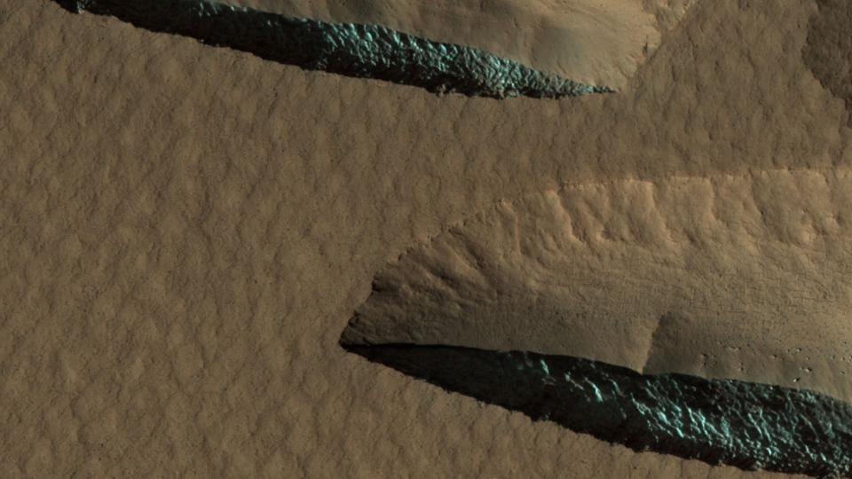 Color photo of two outcrops of blue-green water ice from above