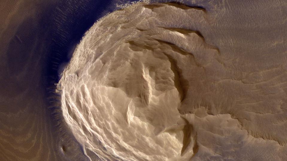 Color photo of a brown, rocky mountain from above, looking straight down at the peak.