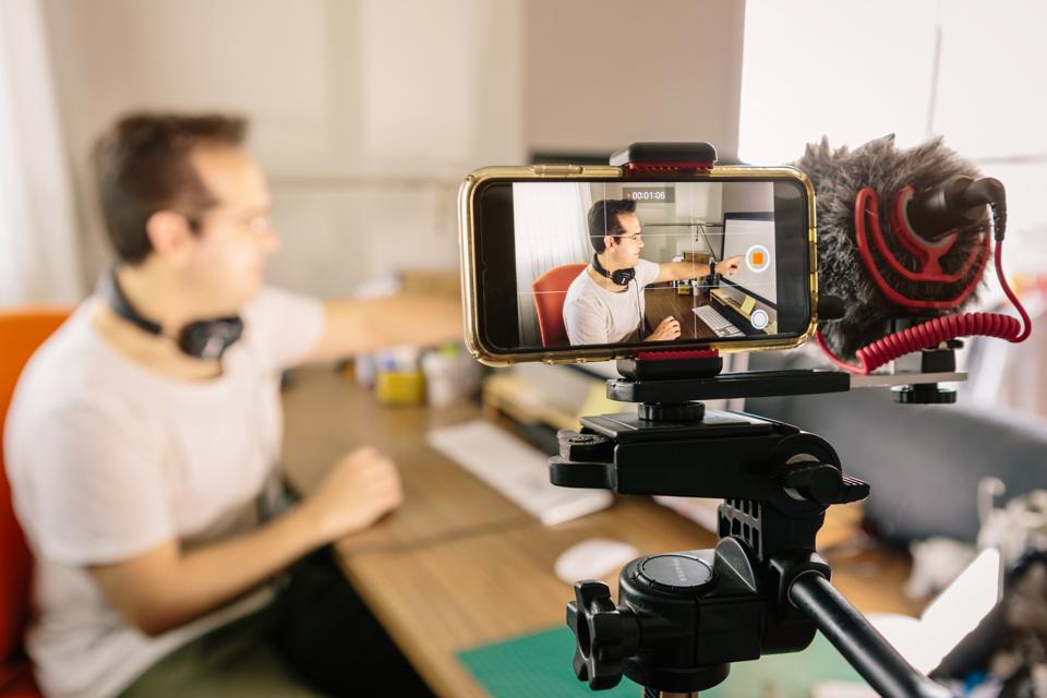 Boy recording with his mobile phone a video for social networks. Use an external microphone to make it easier to hear. Youtube
