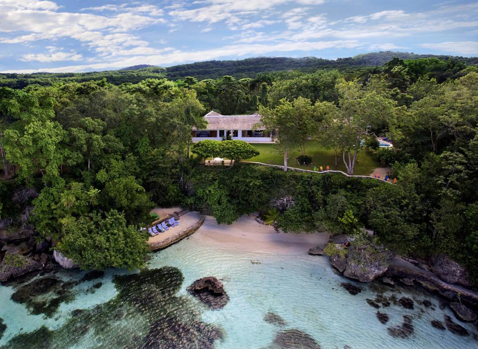 A waterfront villa surrounded by lush foliage overlooking the water