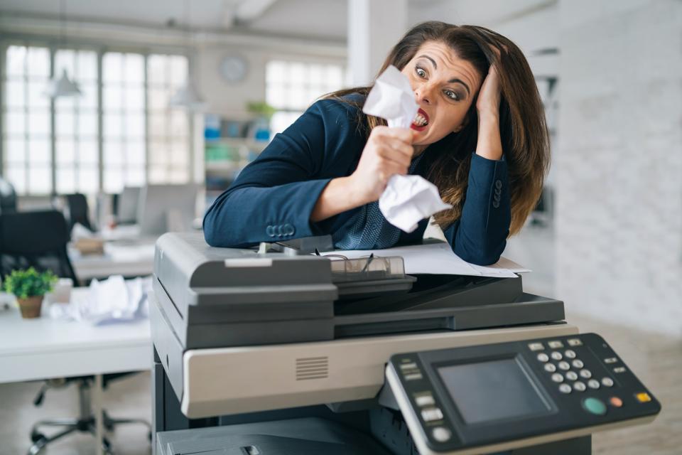 Irritated Business woman standing at printer machine at office