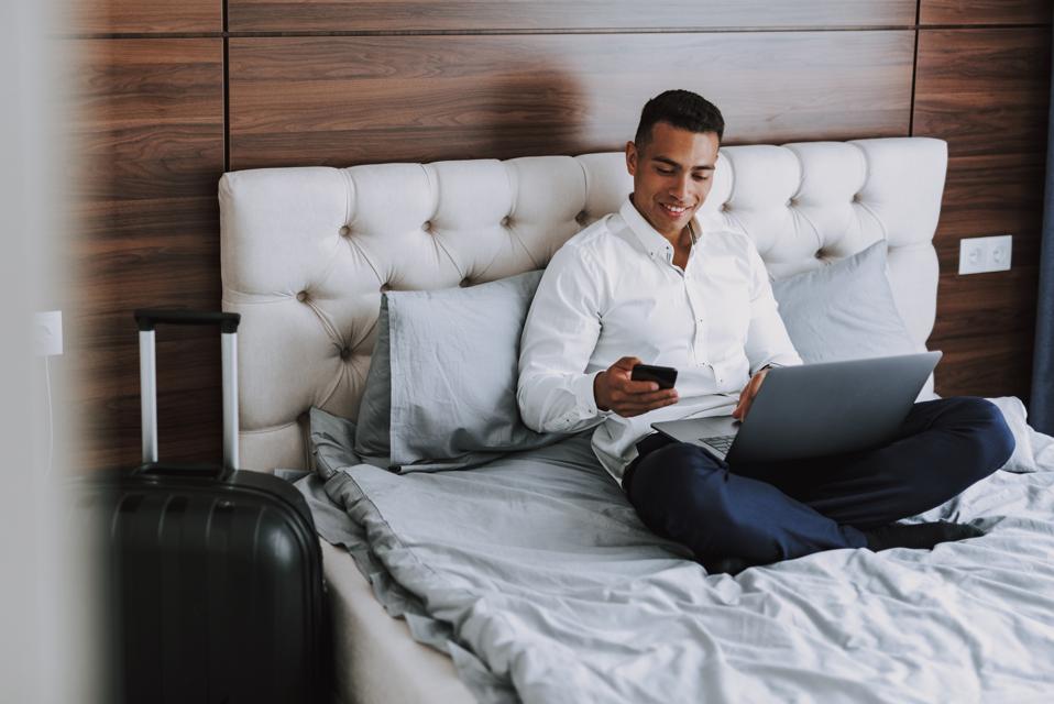 Cheerful man is using modern technologies in hotel room