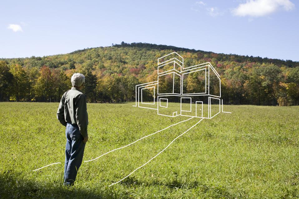 Man standing in field admiring imaginary house