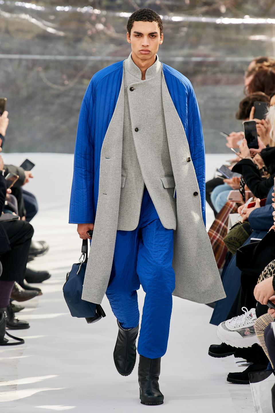 Kenzo: Double faced chiné blanket woolen coat; Double faced chiné blanket woolen jacket; Quilted jogpant in nylon parachute; Aipped crepe boots in grained calf leather; Chesting bag prism in ripstop nylon; Bottle holder on strap in cow leather