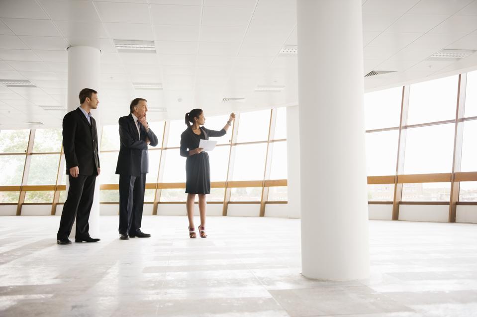 three professionals standing in large open room