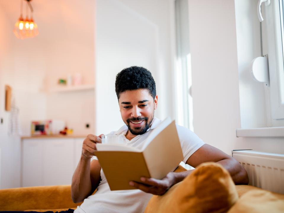 Business leader reading book on sofa of home office