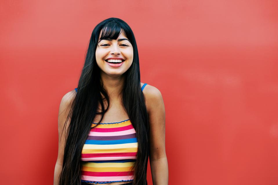 Happy woman looking at camera, red wall