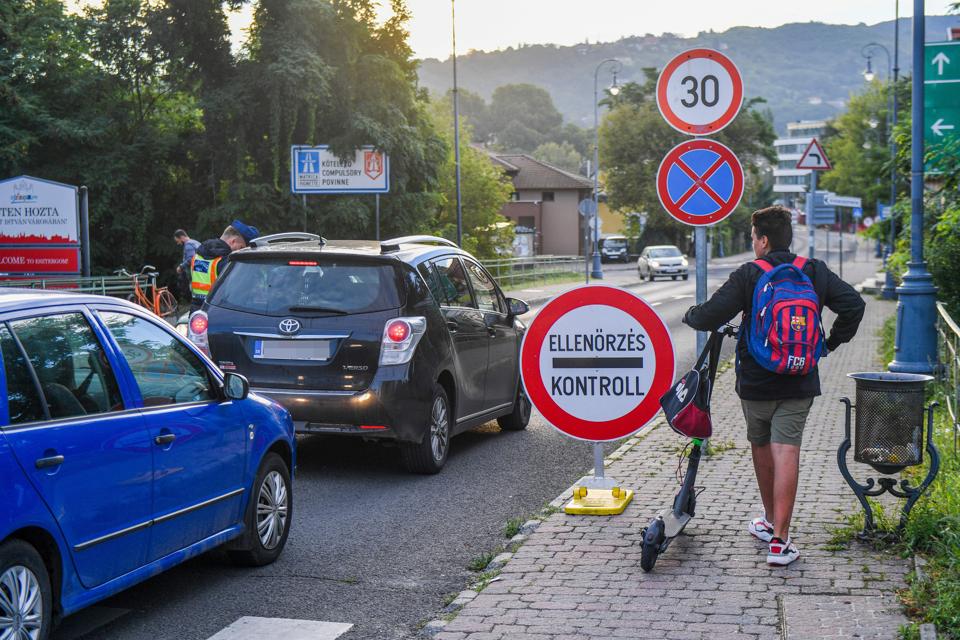A boy on scooter looks on as Hungarian police officers control drivers at border Europe