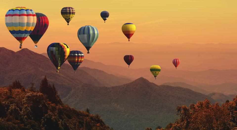 Hot air balloon above high mountain at sunset