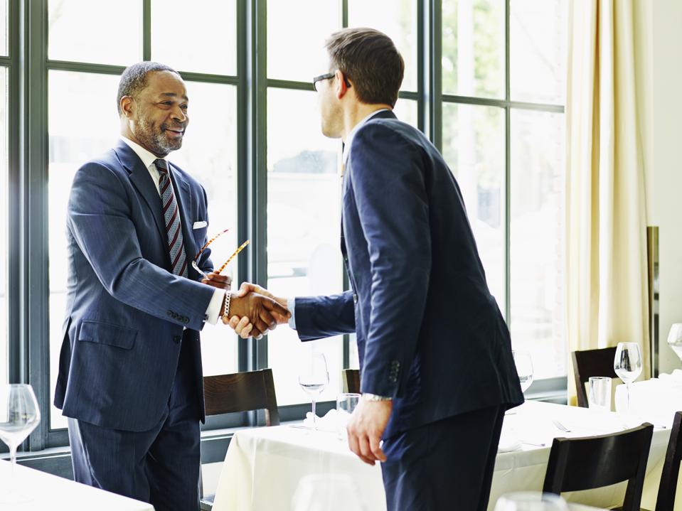 Two businessmen shaking hands at lunch meeting