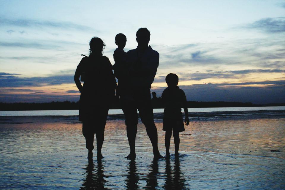 Silhouette Family Standing At Beach Against Sky During Sunset