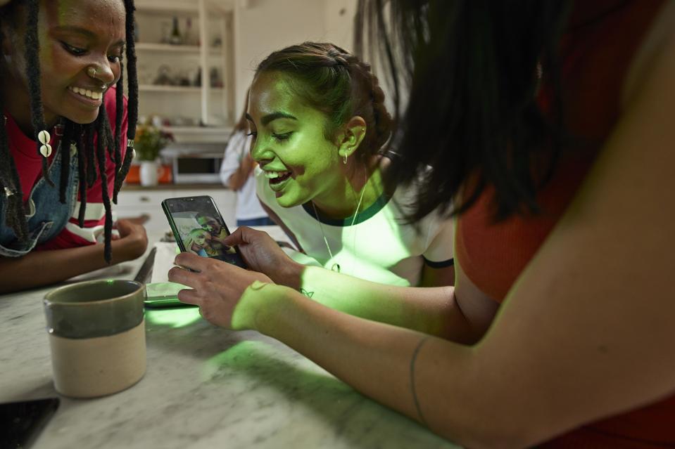 Woman showing photograph to cheerful friends