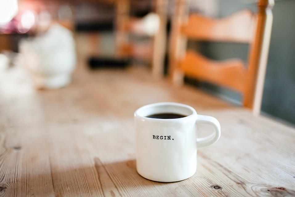 Mug on wood table that reads ″begin″