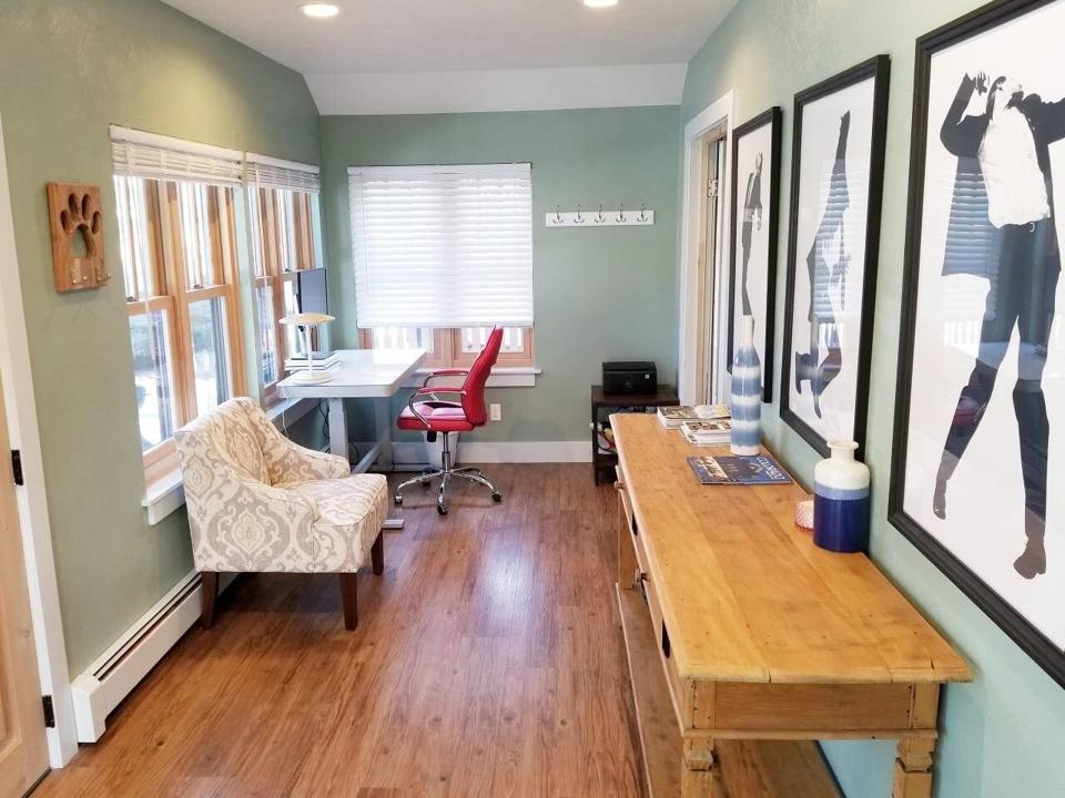 A room in a home with a work desk and some pictures.