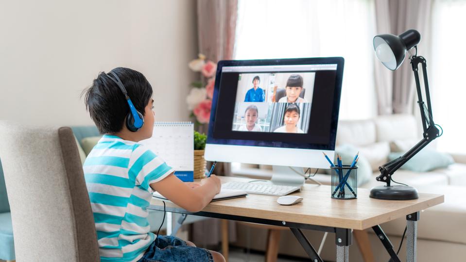 Asian boy student video conference e-learning with teacher and classmates on computer in living room at home