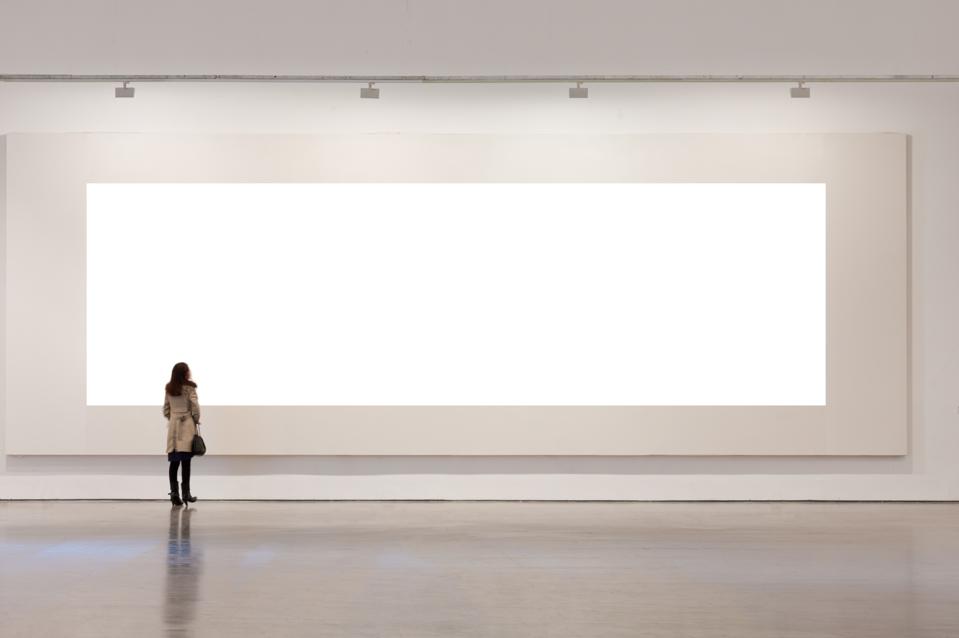 One woman looking at white frame in an art gallery