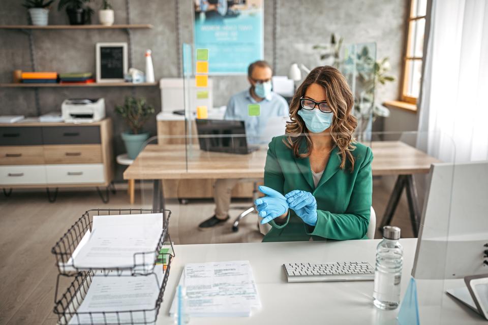 Businesswoman putting on protective gloves in the office