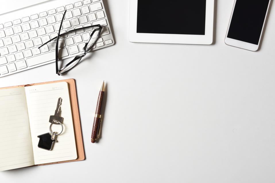 Realtor company office work desk top view with home key, computer keyboard, tablet, smart phone white background