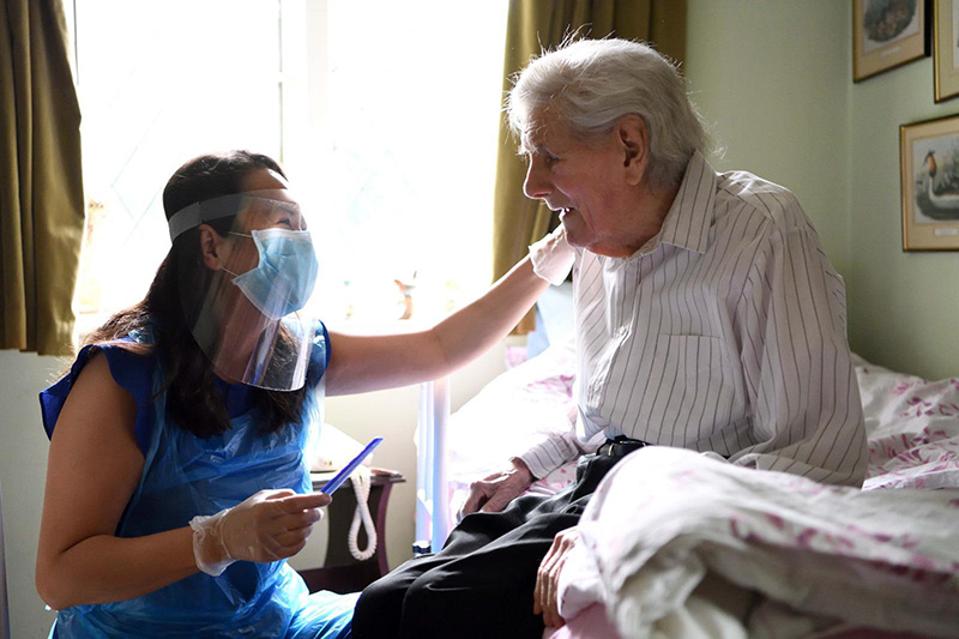 Hold Still Photo Exhibit: a care worker visiting a patient during the pandemic.