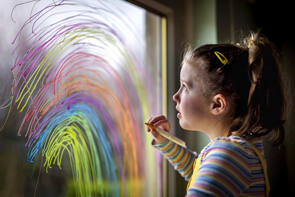 Hols Still; a girl painting a rainbow on a window