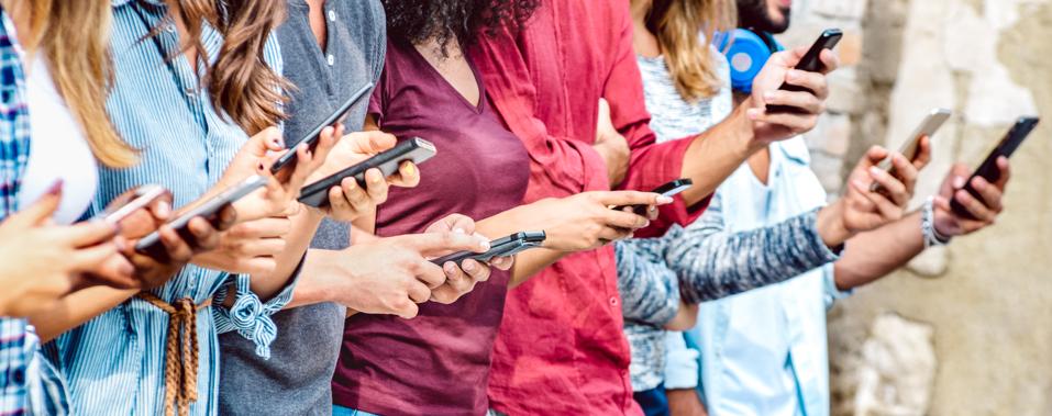Cropped view on millenial hands using mobile smart phones - People addicted by smartphones - Technology concept with always connected teenagers - Shallow depth of field with focus on central device