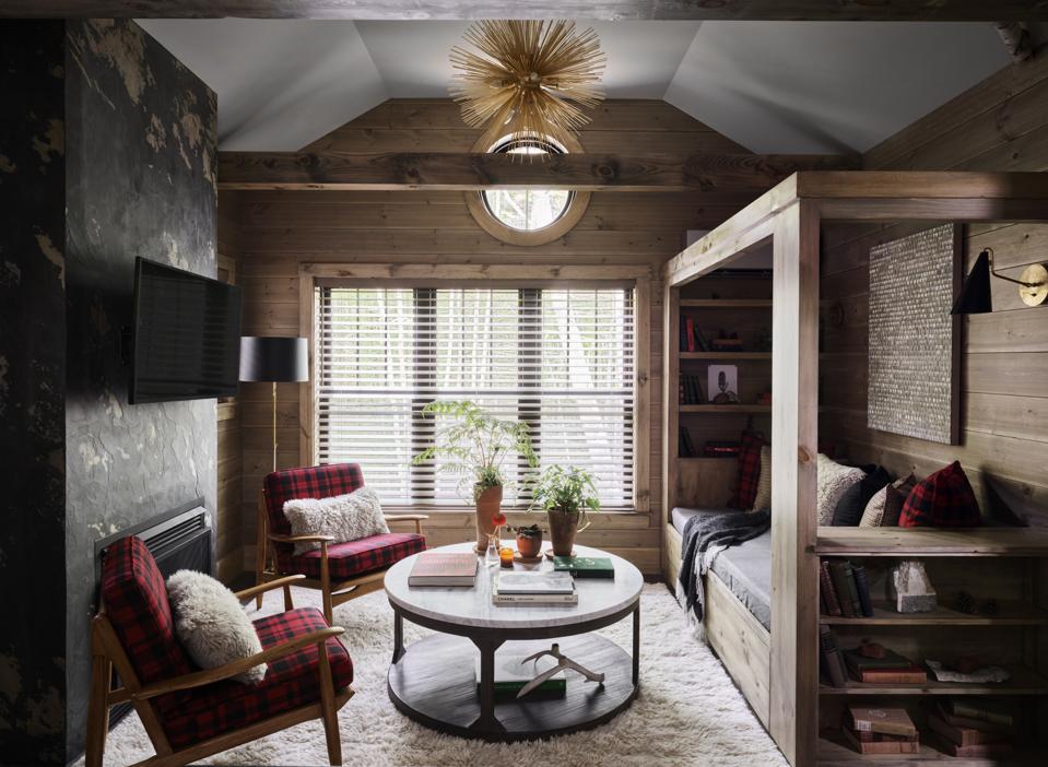 A sitting room with a daybed and two red and black plaid wool covered chairs