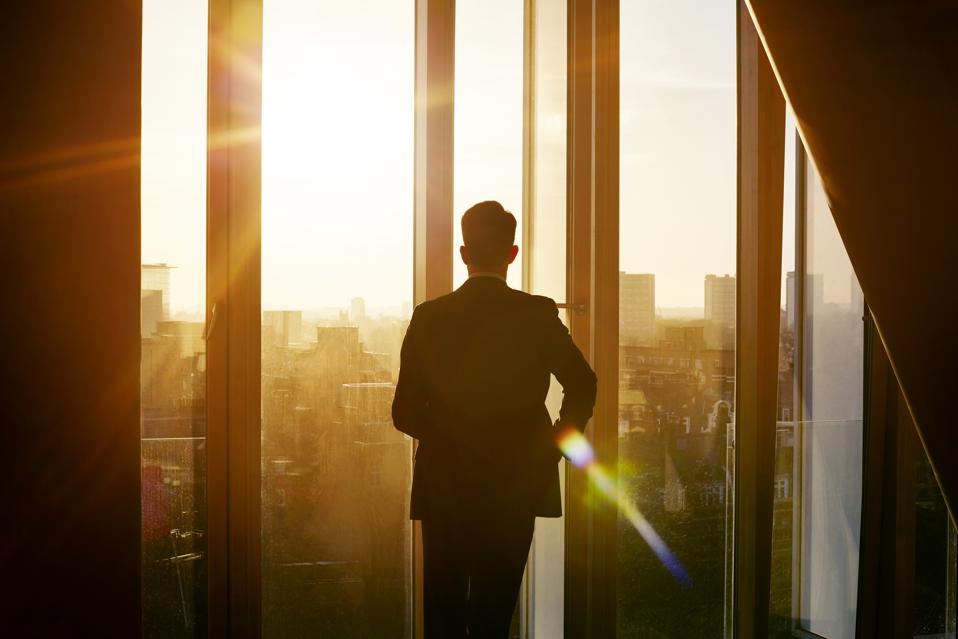 Businessman looking out over city at sunrise