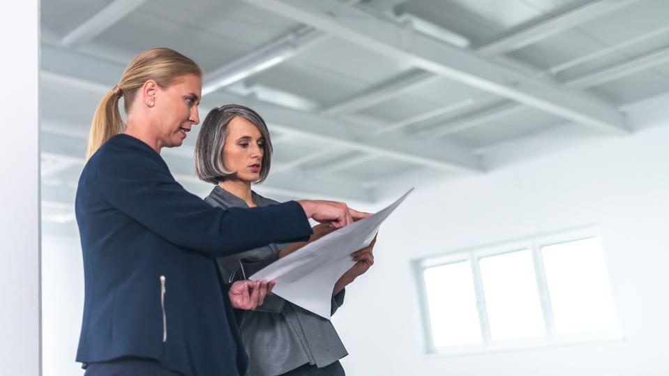 Architect and businesswoman talking in an empty office building