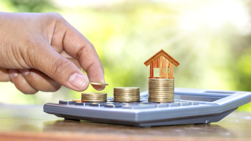 The hand that is holding the coin and free it on the coin stack includes the house model on the coin and a calculator.