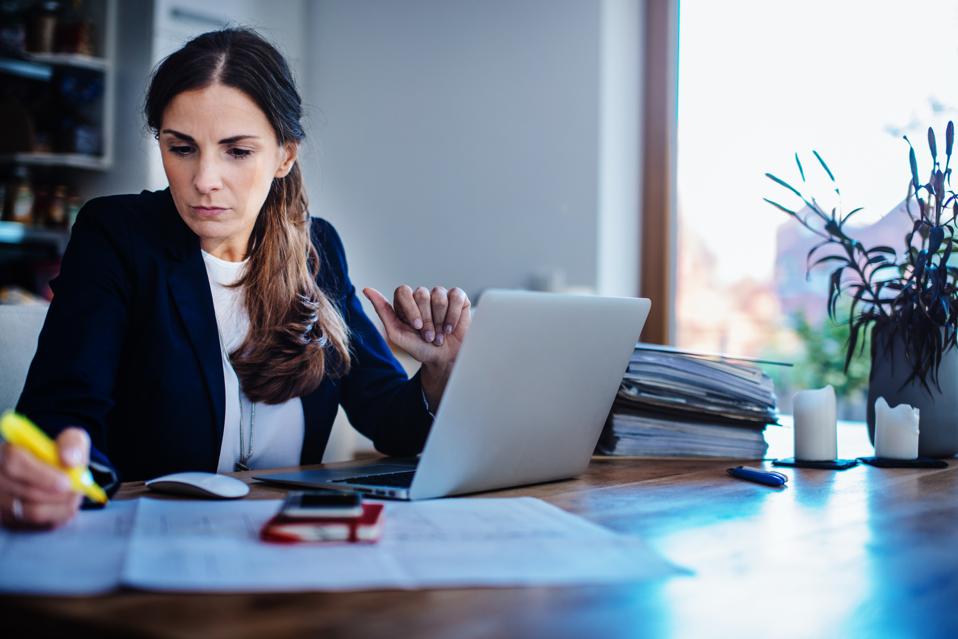 Businesswoman checking plan with laptop at home office.