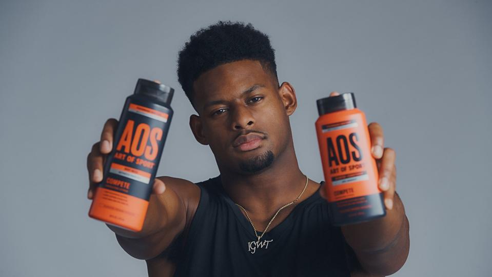 Juju Smith-Schuster, NFL wide receiver, holding bottles of Art of Sport body products in his hands.