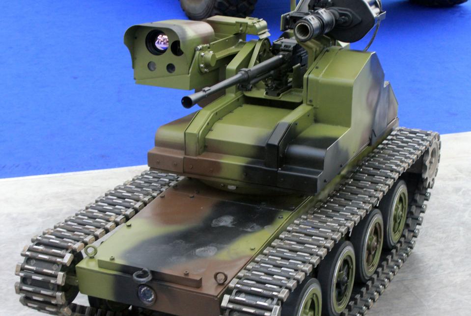 A tracked robot with a gun, a grenade launcher, and several cameras on a turret.