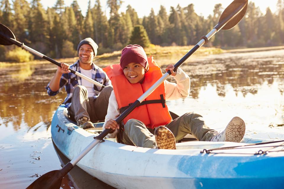 Father And Son Rowing Kayak On Lake. Being near water has health benefits.