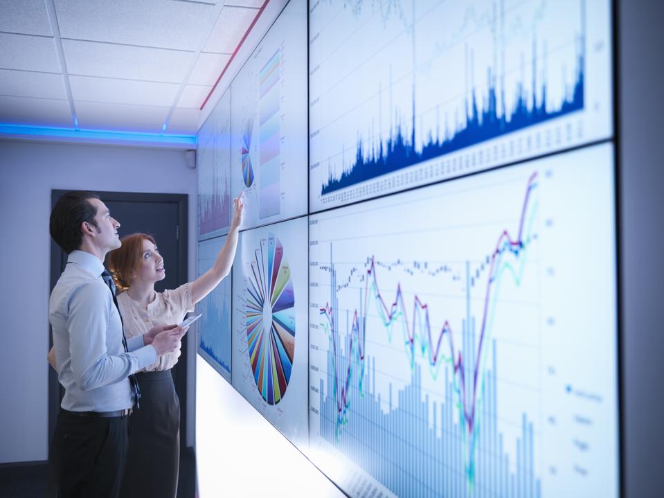 Colegas de negocios estudiando gráficos en pantalla en la sala de reuniones
