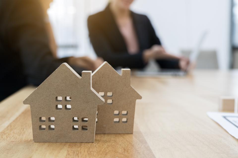Young man and real estate agents look at house plans and bank interest rates on laptops in offices.