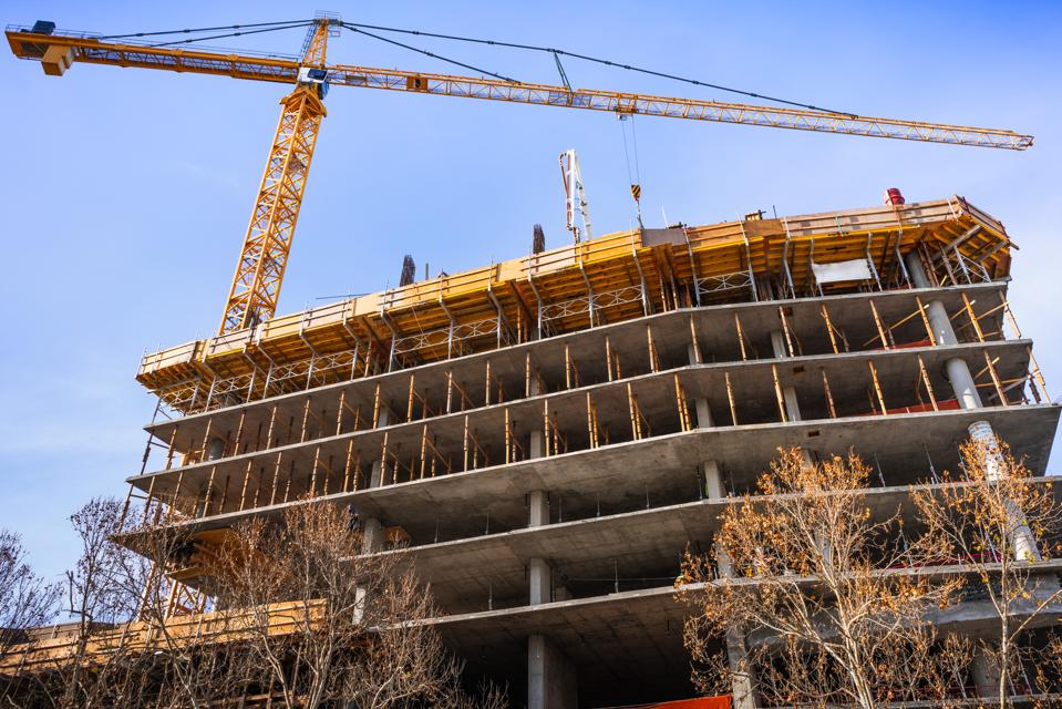 Multi-level concrete building under construction with tower crane; new residential development in the heart of Silicon Valley, San Jose, California