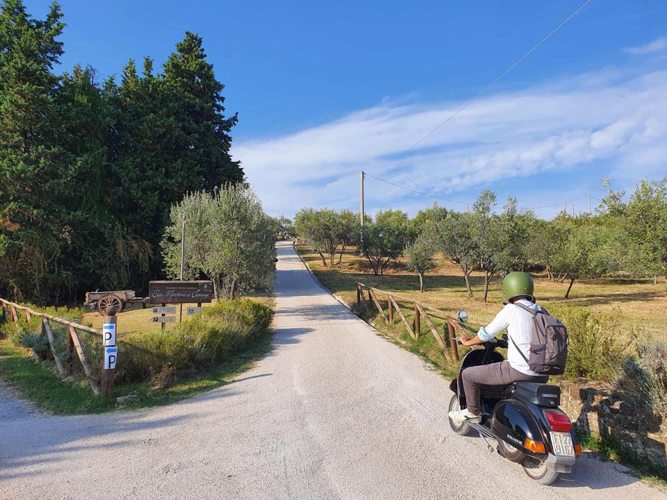 Man rides Vespa along country road Tuscany Italy during Chianti Classico wine festivals