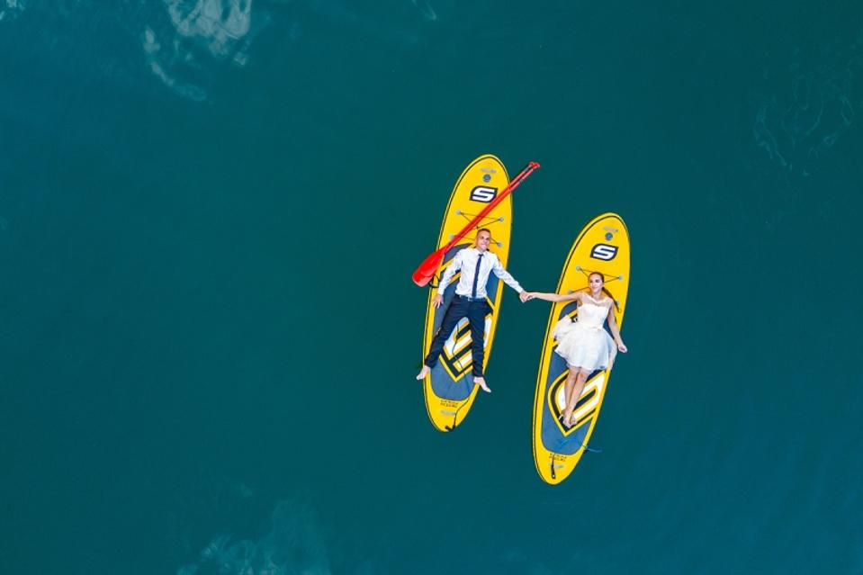 Photo de mariage primée d'un couple flottant sur des planches de surf prises d'en haut avec un drone