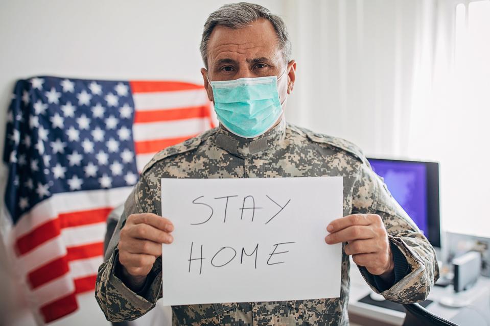 Senior military soldier holding a sign with the message to stay home during the pandemic.