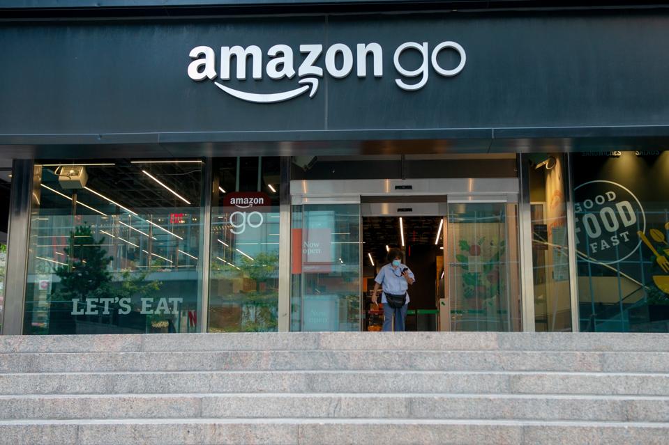 A woman wearing a mask walks out of an Amazon Go store as New York City