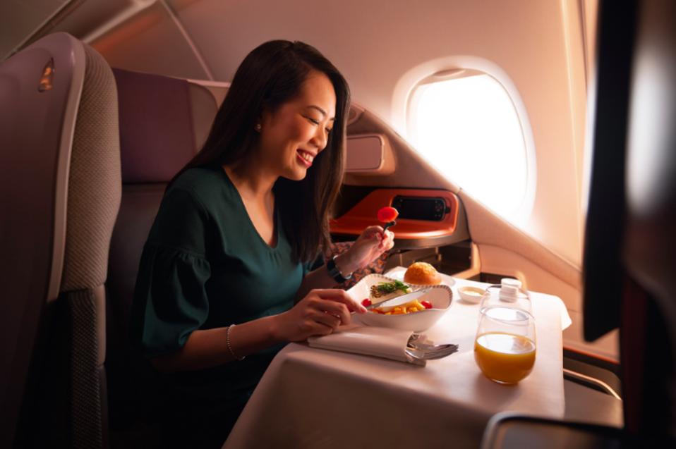 A woman enjoying a business class meal on Singapore Airlines